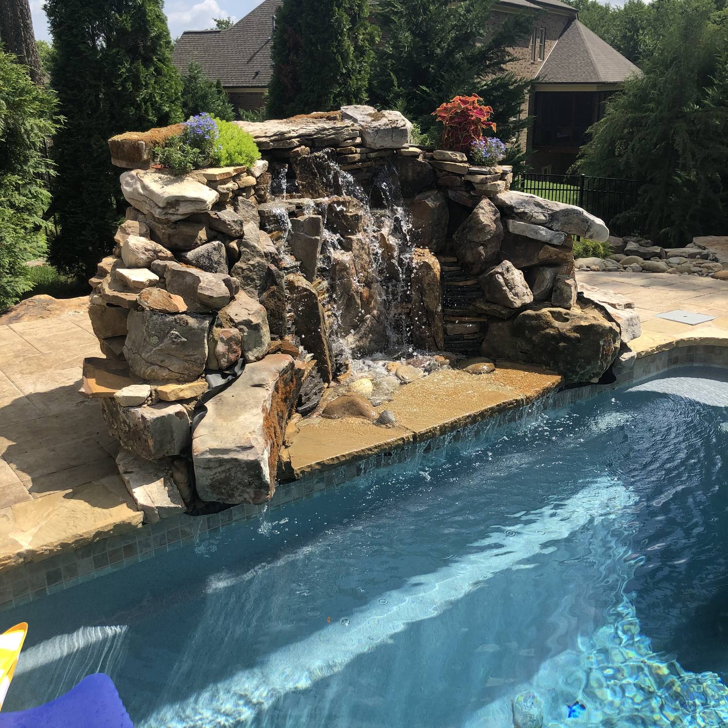 Custom stone waterfall grotto beside pool and spa
